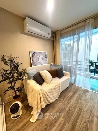 Cozy living room with air conditioning and balcony view, featuring stylish decor and wooden flooring.