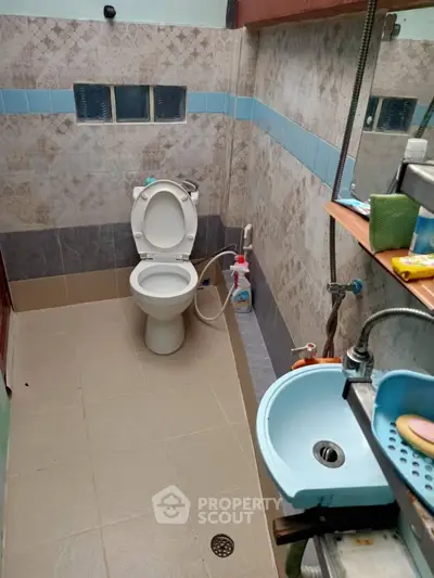 Compact bathroom with modern fixtures and tiled walls, featuring a toilet and a small sink.