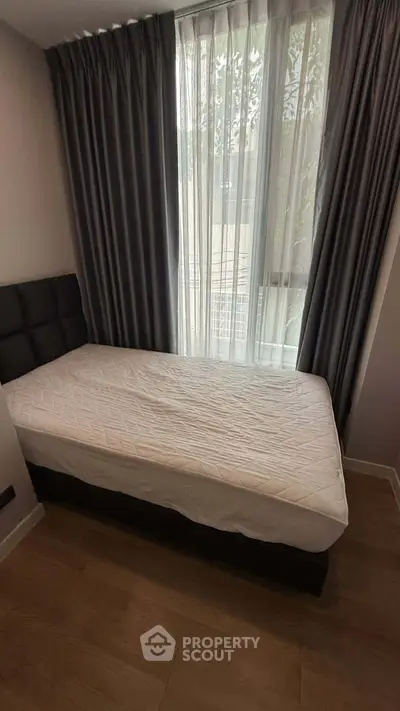 Cozy bedroom with single bed and floor-to-ceiling window with curtains, perfect for natural light lovers.