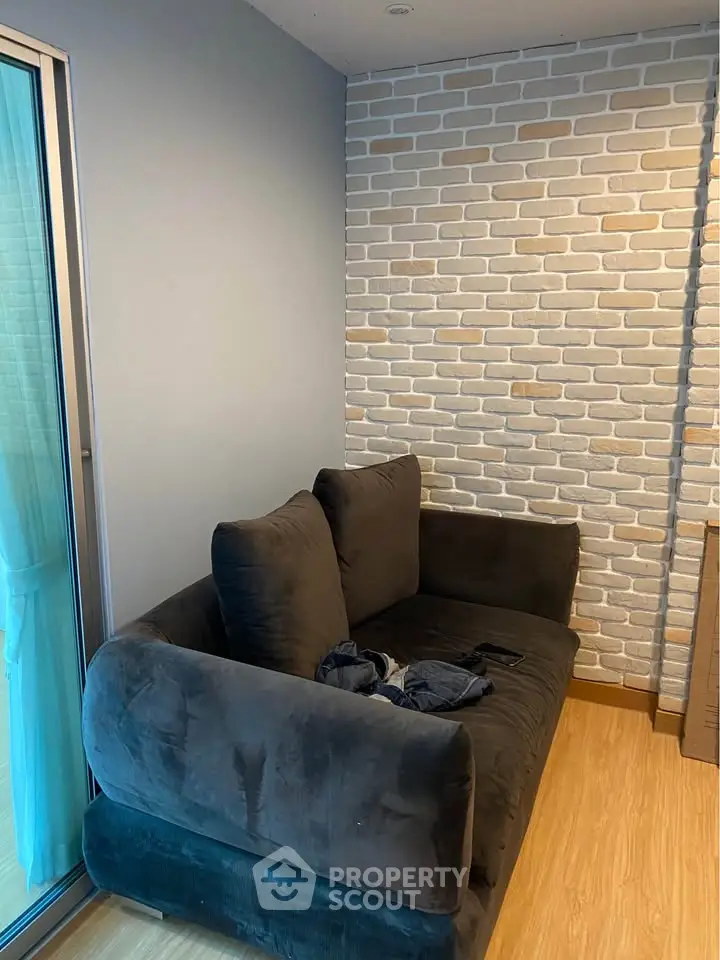 Cozy living room with modern brick accent wall and plush dark sofa, perfect for relaxation.