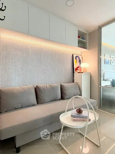 Modern living room with sleek gray sofa, stylish lighting, and contemporary decor for a cozy ambiance.