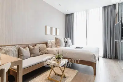 Modern bedroom with elegant decor, large windows, and cozy seating area in a stylish apartment.