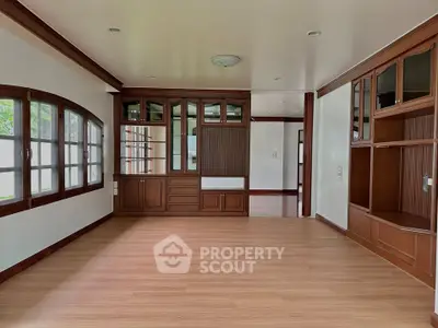 Spacious living room with elegant wooden built-in cabinets and large windows
