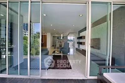 Spacious modern living room with open layout and large glass doors leading to balcony.