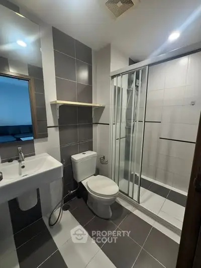 Modern bathroom with sleek design, featuring a glass shower enclosure and contemporary fixtures.