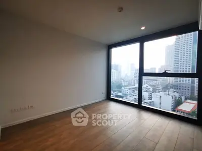 Spacious empty room with large window offering stunning cityscape views, perfect for modern urban living.