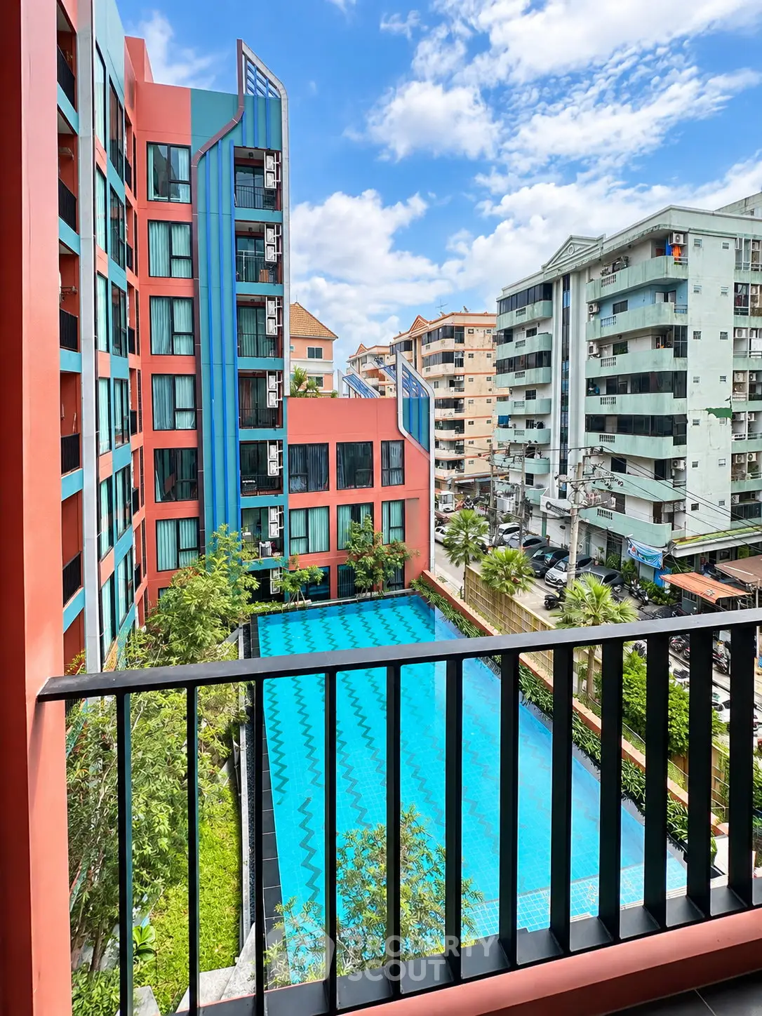 Stunning view from balcony overlooking modern apartment complex with pool and vibrant architecture.