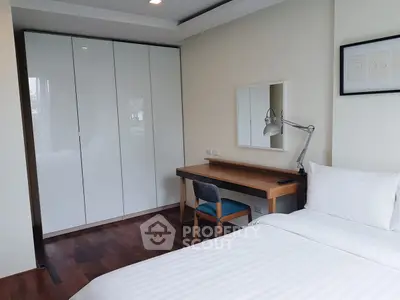 Modern bedroom with sleek white wardrobe and cozy workspace