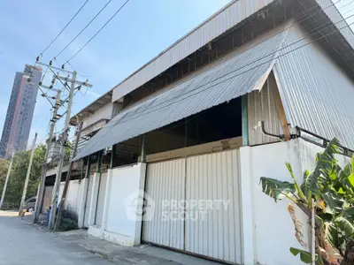 Spacious industrial warehouse with large metal doors and urban surroundings, ideal for business operations.