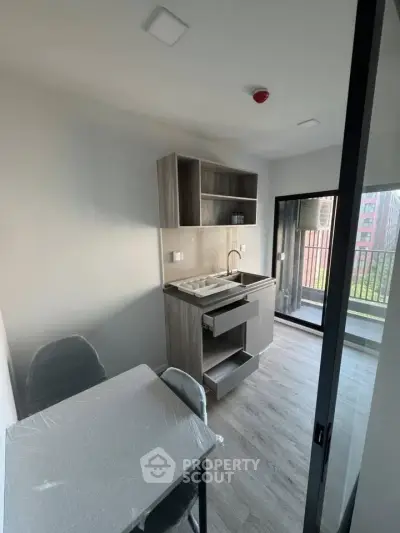 Modern compact kitchen with balcony access in urban apartment