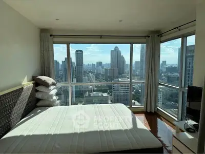 Stunning bedroom with panoramic city view and large windows in a high-rise apartment.