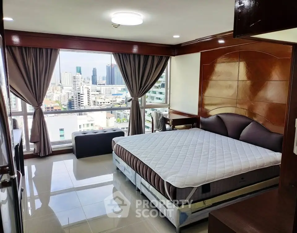 Luxurious bedroom with stunning city view and elegant furnishings in high-rise apartment.