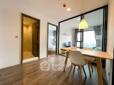 Modern apartment interior with open living and dining area, featuring wooden flooring and stylish lighting.