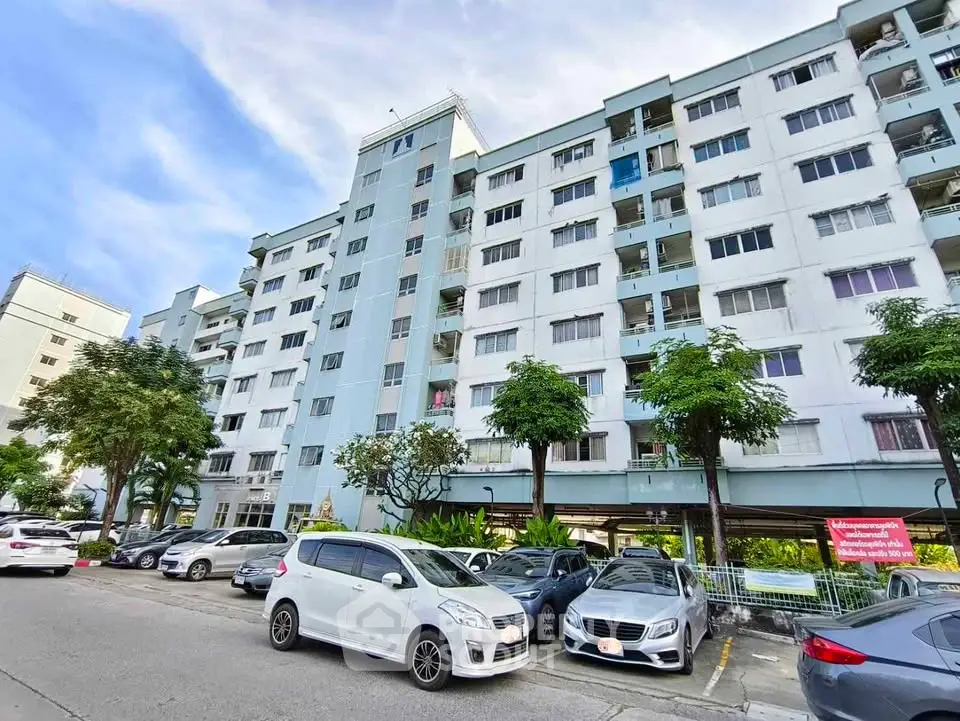 Spacious apartment building with ample parking and lush greenery, perfect for urban living.