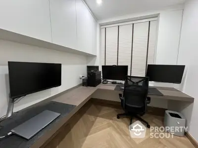 Modern home office with sleek desk, multiple monitors, and ergonomic chair