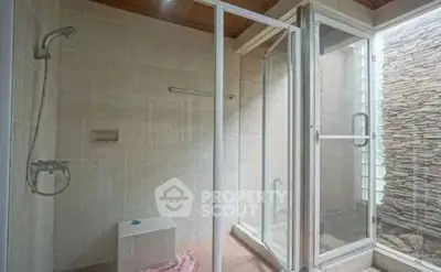Spacious modern bathroom with glass shower enclosure and stone accent wall.