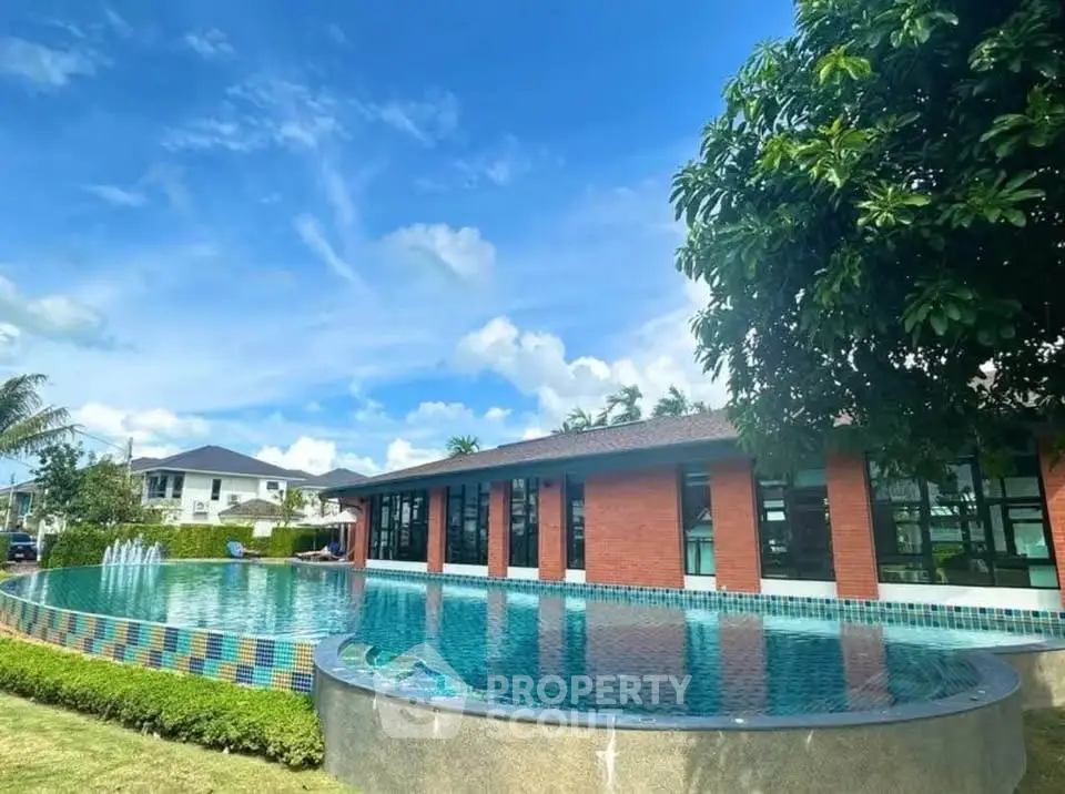 Luxurious residential pool with modern architecture and lush greenery under a clear blue sky.