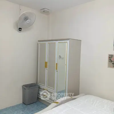 Cozy bedroom with wardrobe and wall-mounted fan, ideal for comfortable living.