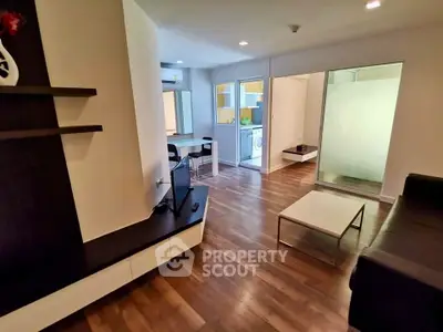 Modern living room with sleek furniture and open layout, featuring hardwood floors and bright lighting.
