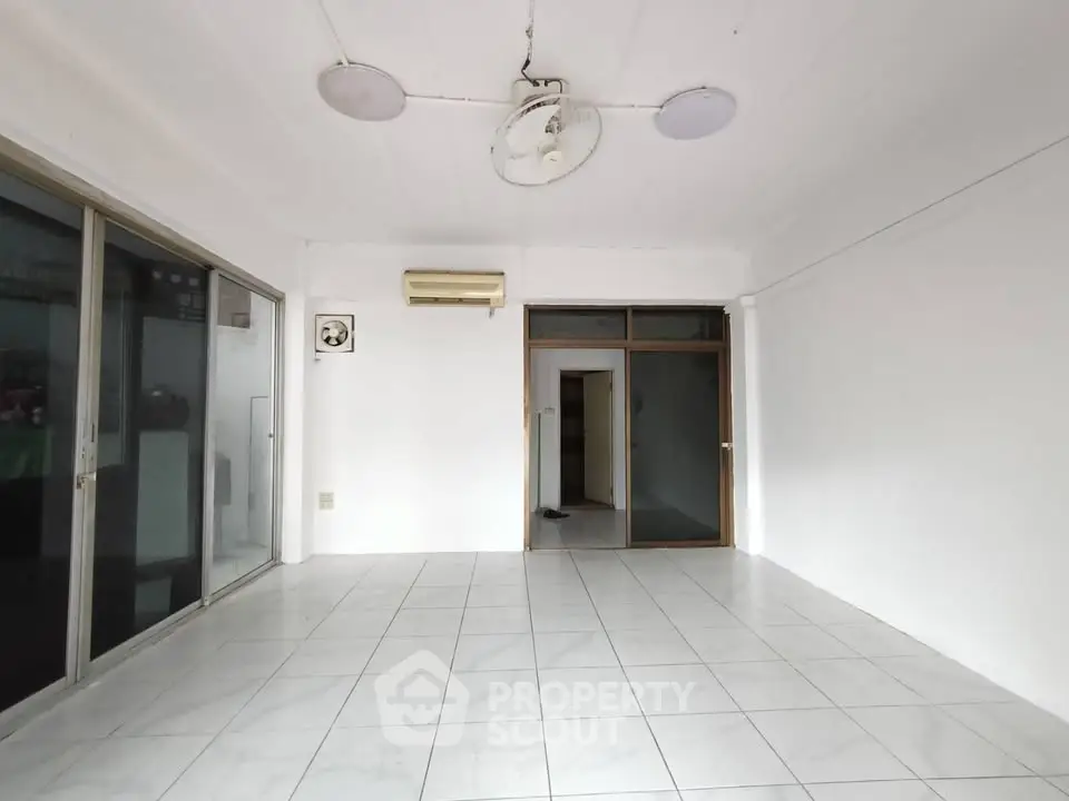 Spacious empty room with tiled floor and large windows, ideal for customization.