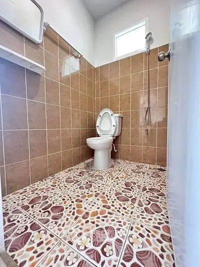 Modern bathroom with tiled walls and floor, featuring a toilet and shower area.