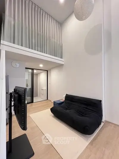 Modern loft-style living room with high ceilings and sleek black sofa