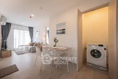 Modern open-plan living room with dining area and washing machine in stylish apartment.