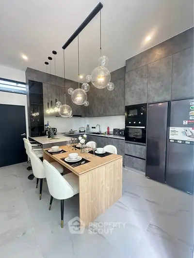 Modern kitchen with sleek design, featuring a dining island, pendant lights, and built-in appliances.
