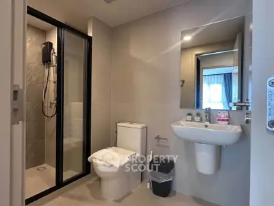 Modern bathroom with sleek fixtures and glass shower enclosure in a contemporary apartment.