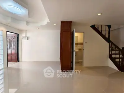 Spacious open-plan living area with modern staircase and tiled flooring