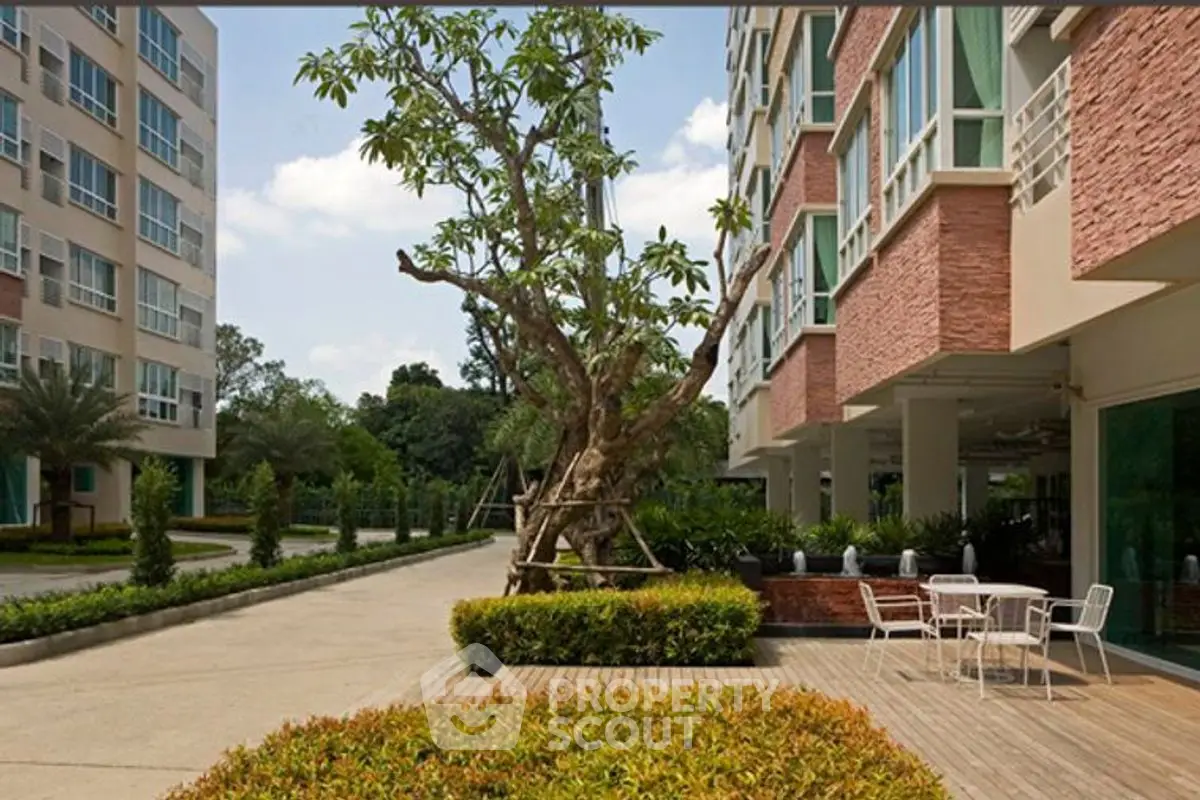 Modern apartment building with landscaped garden and outdoor seating area.