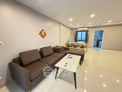 Spacious modern living room with elegant brown sofa and dining area, perfect for family gatherings.