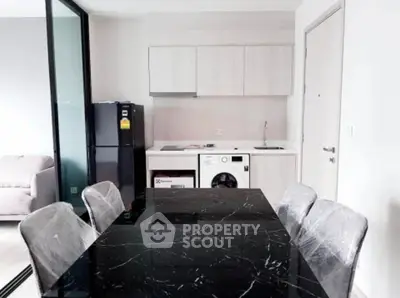 Modern dining area with sleek black marble table and integrated kitchen appliances.
