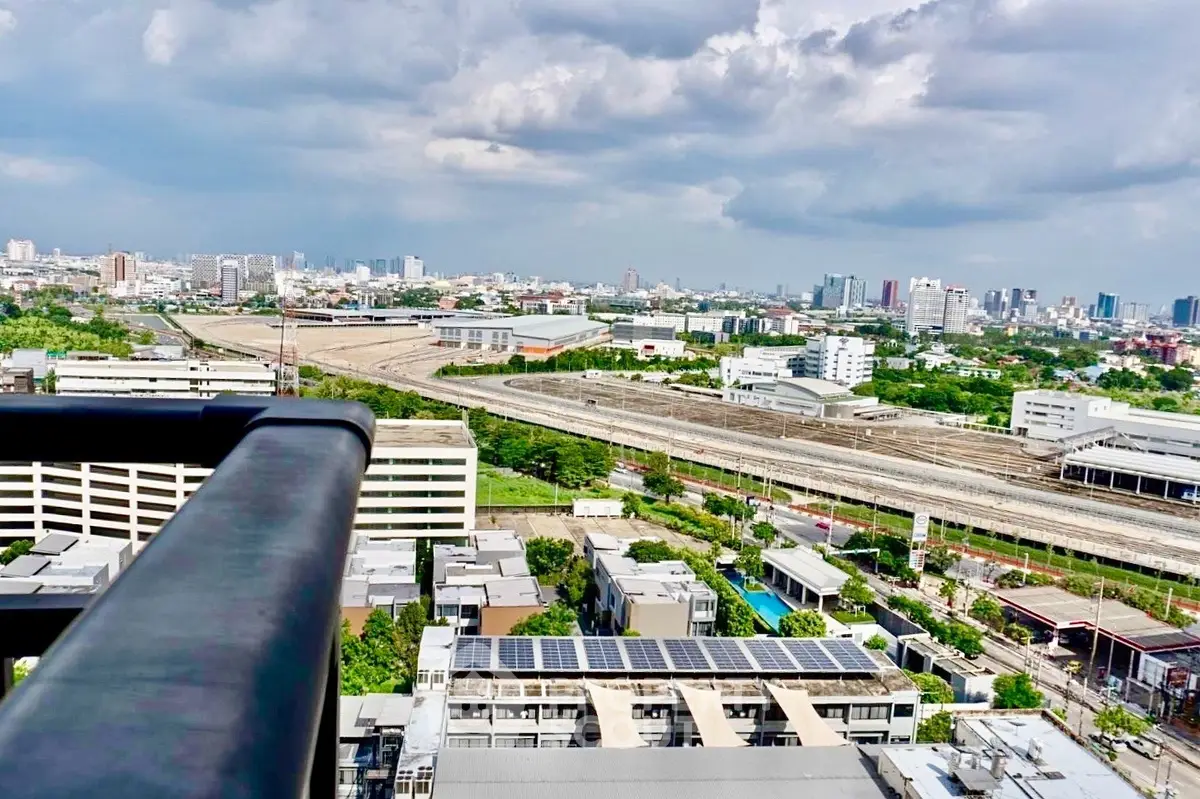Stunning cityscape view from a high-rise balcony showcasing urban skyline and railway tracks.