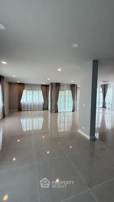 Spacious modern living room with large windows and elegant curtains