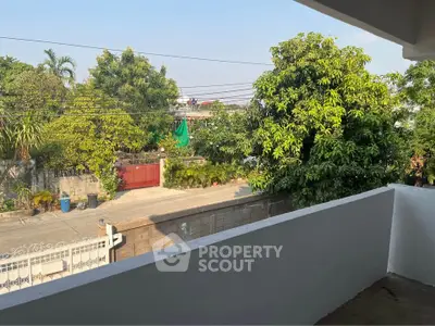 Charming balcony view with lush greenery and quiet neighborhood street.