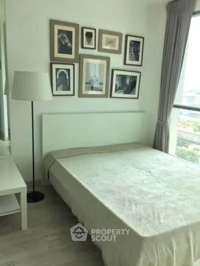 Bright bedroom with large window and stylish wall art in modern apartment.