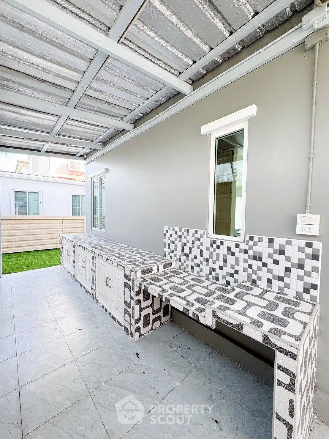 Modern outdoor kitchen with tiled countertops and covered roof, perfect for entertaining.