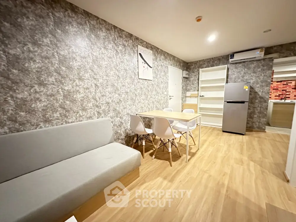 Modern living room with stylish decor and dining area, featuring a sleek fridge and contemporary furniture.