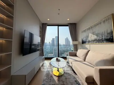 Modern living room with city view, stylish sofa, and wall art in high-rise apartment.