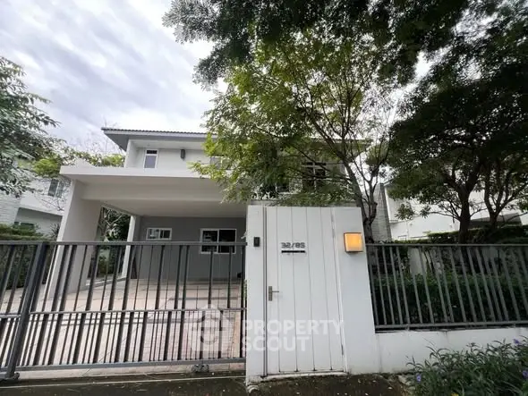 Modern two-story house with gated entrance and driveway in a serene neighborhood.