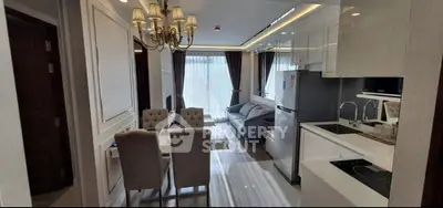 Luxurious open-plan living room and kitchen with elegant chandelier and modern furnishings.