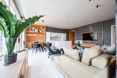 Luxurious modern living room with open kitchen, elegant decor, and large windows offering natural light.
