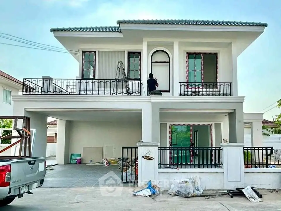 Modern two-story house with balcony and garage in suburban neighborhood.