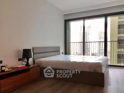 Modern bedroom with large window and city view, featuring a stylish bed and wooden flooring.