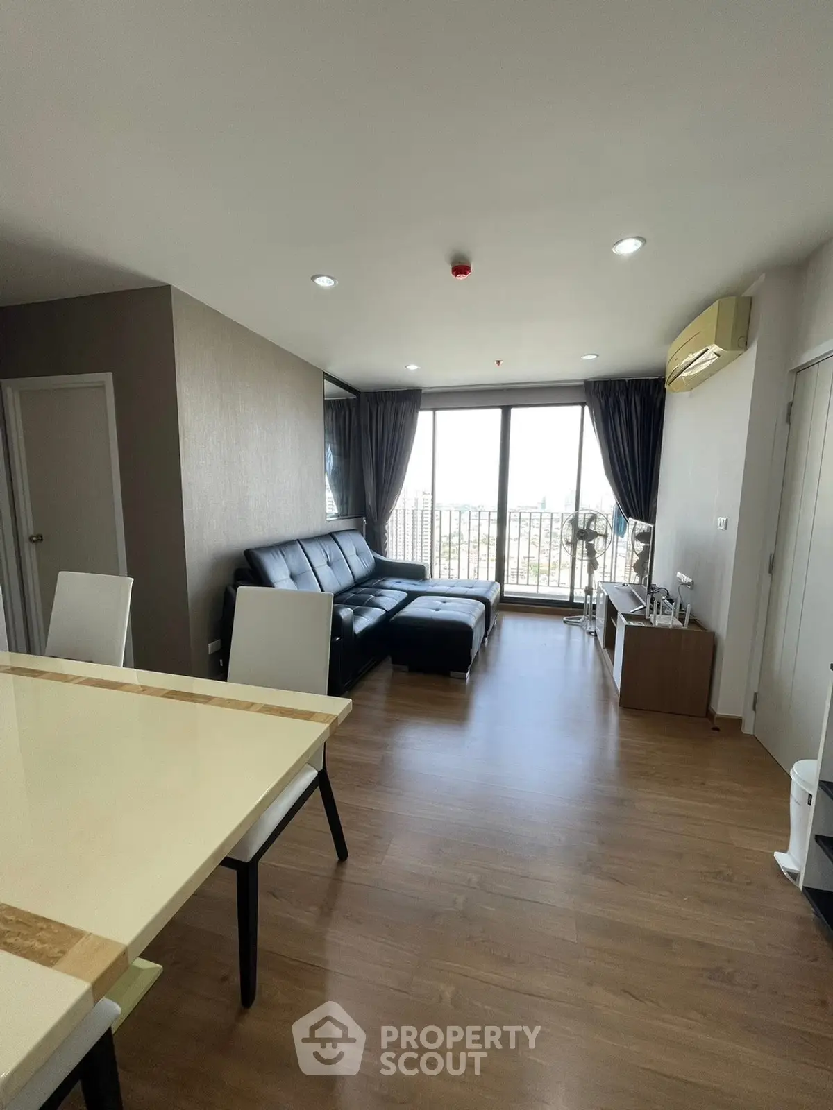 Modern living room with sleek furniture and large windows offering city views.