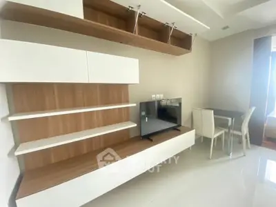 Modern living room with sleek TV unit and dining area in a bright, minimalist apartment.