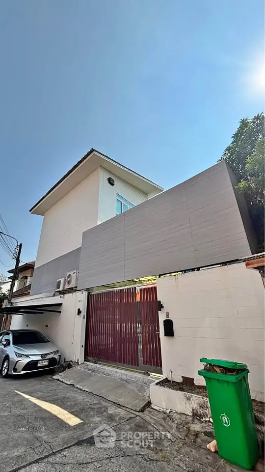 Modern two-story house with gated entrance and driveway in a suburban neighborhood.
