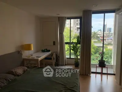 Cozy bedroom with large window offering city view, modern decor, and natural light.