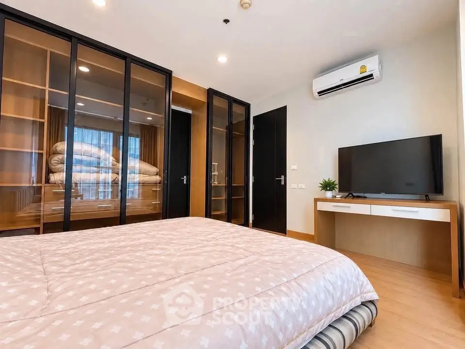 Modern bedroom with glass wardrobe and air conditioning in a stylish apartment.
